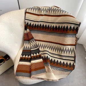 Bohemian thick cashmere-like scarf with geometric patterns and fringe on a soft chair