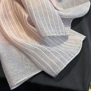 Gros plan d'une écharpe en soie et laine dégradée rose et grise avec texture rayée