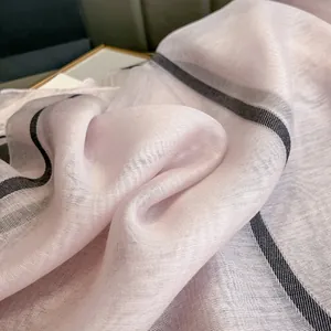 Vue macro de la texture d'un foulard en soie rose clair avec des rayures noires fines