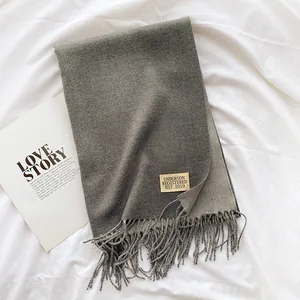 Close-up of thick dark grey scarf texture with long tassels and woven brand label