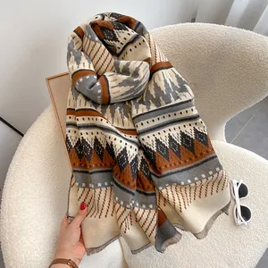 Detail of bohemian geometric scarf with dense fringe on a cozy white armchair