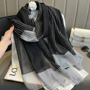 Détail d'une élégante écharpe en soie et laine à rayures noir et gris, texture fine