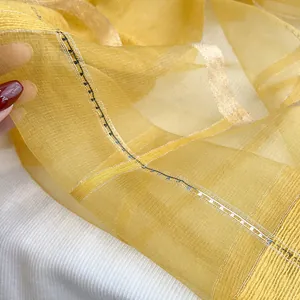Macro detail of translucent yellow silk mohair scarf with golden metallic thread texture