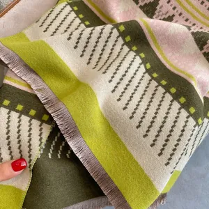 Detail of bohemian cashmere-feel scarf with geometric knit patterns and brown tassels
