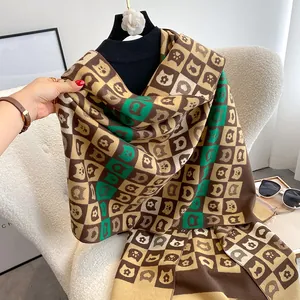 Détail d'une écharpe à carreaux douce avec motifs chats sur un col roulé noir