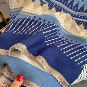Detail of bohemian cashmere-like scarf showing blue geometric wave patterns and fine tassels