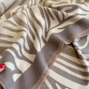 Dettaglio dello scialle spesso con motivo zebrato moka e beige con frange