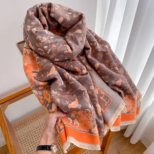 Detail of floral bird print scarf with orange trim and tassels on a wicker chair