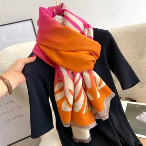 Dettaglio di sciarpa pashmina con motivo a foglie rosa e arancio e bordi sfrangiati