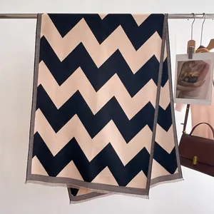 Thick wave pattern knitted scarf with tassels in black and beige, draped over a rack