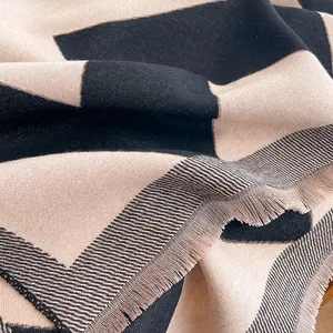 Detailed close-up of woven twill texture and fringe edges on black and beige scarf
