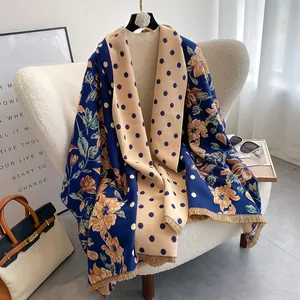 Detail of floral and polka dot double-sided scarf with fine fringe on a sofa
