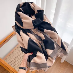 Close-up of thick winter scarf featuring black and khaki geometric pattern with tassels