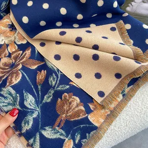 Close-up of ethnic floral and polka dot patterns on a thick fringed pashmina scarf