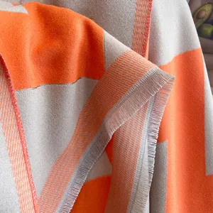 Detail shot of the orange and gray geometric knit scarf with soft fringe edges