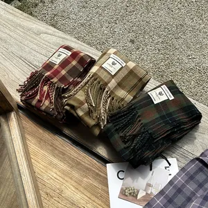 Classic checkered plaid scarf with fringe tassels stacked on a wooden bench