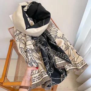 Detailed view of reversible black and beige scarf with artistic print and fringe edges