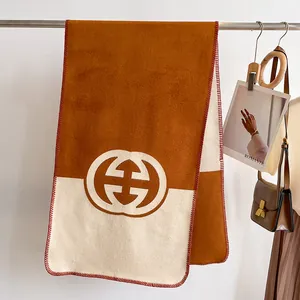 Detail of soft cashmere feel scarf with bi-color stitching and round logo detail