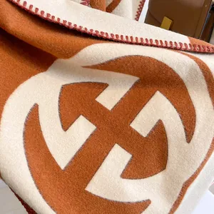 Close-up of soft cashmere-like scarf fabric with geometric logo and stitched edges