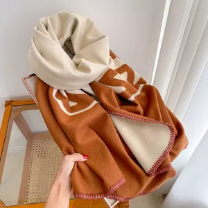 Detail of soft double-sided cashmere-like scarf with large monogram and stitched edges