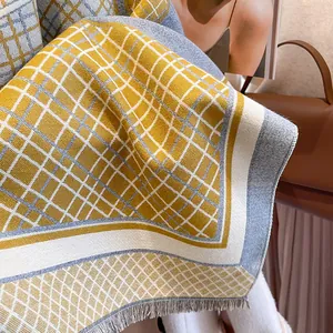 Close-up of yellow and grey plaid knit scarf with fine tassel fringe and thick texture