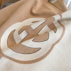 Detailed macro view of double-sided cashmere-style scarf with H logo and contrast stitching
