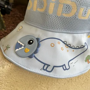 Detailed macro view of children's sun hat featuring a 3D silicone dinosaur and mesh fabric
