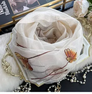 Detail of silk blend scarf with floral embroidery, sequins and beadwork on a white tray