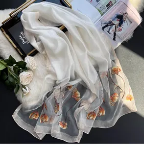 Close-up of white silk scarf with orange tulip embroidery and beaded accents