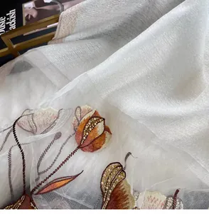 Close-up of elegant floral embroidery and pearl beading on white silk blend scarf fabric