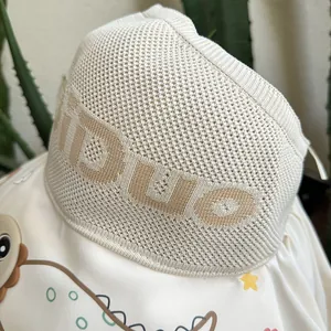 Detail of baby knit hat in beige featuring KIDUO text embroidery and soft texture