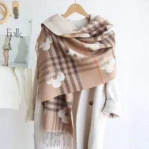 Detail of checkered cashmere-feel shawl with flower pattern and fringe on white coat