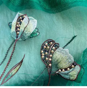 Detailed embroidery on green silk shawl featuring floral beadwork and pearls