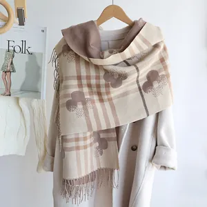 Detail of floral patterned cashmere-like scarf with long fringe and plaid texture