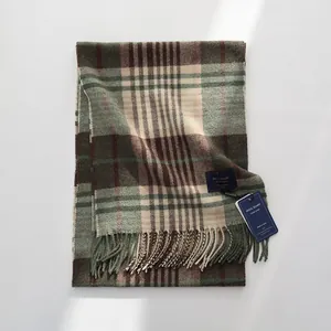 Detailopname van klassieke wollen geruite sjaal in groen en beige met franjes en label