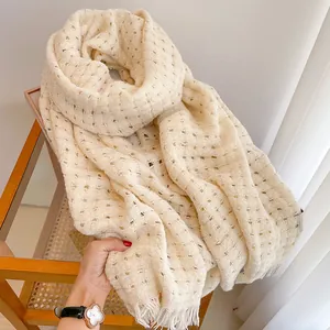 Detail van beige opengewerkte wollen sjaal met rastertextuur en zachte franjes