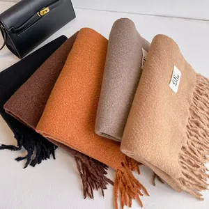 Close-up of fringe details and brand labels on multi-color thick cashmere scarves