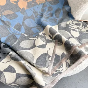 Dettaglio di sciarpa floreale in finto cashmere con frange su un divano bianco testurizzato