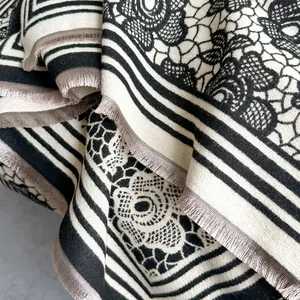 Close-up of thick cashmere-like scarf with black and white floral patterns and grey tassels