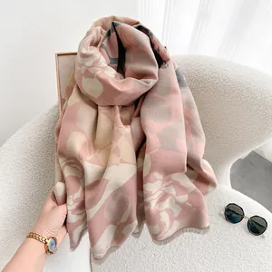 Scialle in cashmere con fiori rosa e grigi e frange su sedia bianca