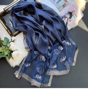 Detailed embroidery and beaded floral patterns on dark blue silk blend scarf texture