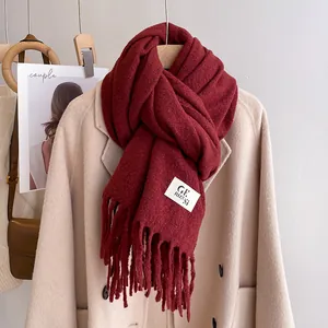 Detail of dark red knitted scarf with tassels and brand label on a coat
