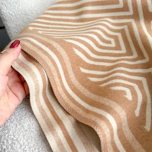 Makroansicht des beigen Labyrinth-Geometriemusters und der dicken Strickstruktur des Schals