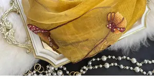 Close-up of mustard silk blend scarf with exquisite floral embroidery and hand-beaded pearls