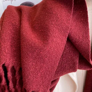 Detailed macro view of deep red knitted scarf texture with wool tassel fringe