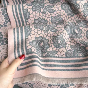 Close-up of thick pink and grey cashmere-feel scarf with floral jacquard and fringe edges