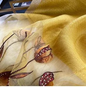 Macro view of golden silk blend fabric with floral embroidery and handmade beadwork