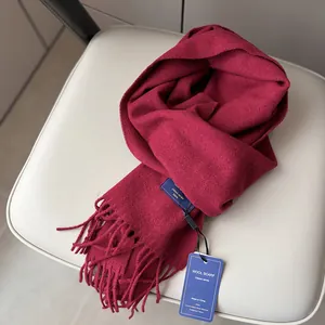 Detailed macro view of deep red wool scarf featuring classic woven label and long tassels
