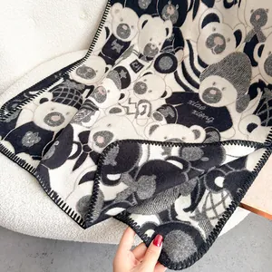 Detailed view of heavy knit bear pattern scarf with fine overlock stitching and soft texture