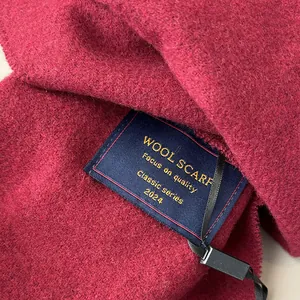 Detail shot of the woven wool scarf label and premium crimson red fabric texture